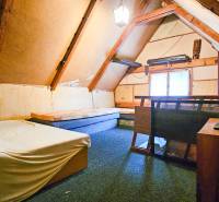 Attic room in a cottage with a bed and a TV on wooden furniture.