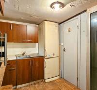A kitchen in a cottage with a countertop, refrigerator, and sink. Floor with wooden decor.