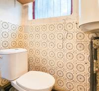 A toilet with a heater, tiles on the wall, in a cabin.