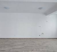 An empty room in a family house with white walls and a wooden-patterned floor.