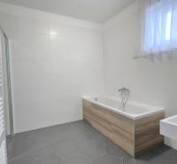 A bathroom in a family house with a bathtub featuring a wooden decor and white tiles.