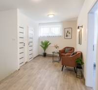 Interior of a family house with a wooden decor floor, comfortable armchairs, and plants.