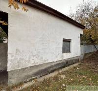 A family house in Zemné with a plastered facade, surrounded by autumn trees and grass.