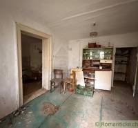 An abandoned room in a family house with furniture and a worn-out floor.