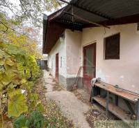 The exterior of a family house in Zemné with old plaster and a shelter.