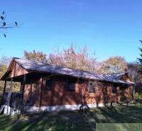 A wooden cottage in Dudince surrounded by autumn nature and a blue sky.