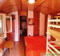 The interior of a cabin with a bunk bed, a wood-patterned floor, and an open window.