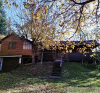 A cottage in Dudince surrounded by autumn leaves and trees.