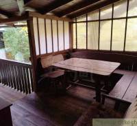 Covered terrace at the cottage with wooden decor and wooden seating.