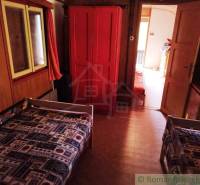 The interior of a cabin with two beds, a red wardrobe, and a carpet with a geometric pattern.