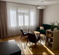 Living room in a 3-room apartment with a wooden decor floor, green sofa, wooden chairs.