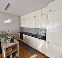 A kitchen in a 3-room apartment with white cabinets and a wooden decor floor.