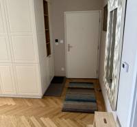 Entrance hall in a 3-room apartment with wood-patterned flooring and white furniture.