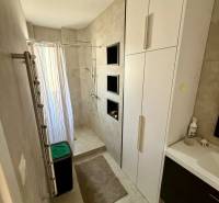 A bathroom in a 3-room apartment with a shower, cabinets, and beige walls.