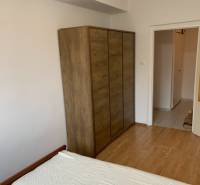Bedroom in a 2-room apartment with a bed, wardrobe, and floor with a wooden decor.