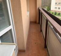 A balcony in a 2-room apartment with tiles and glass doors.