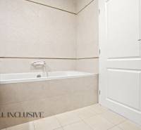 Bathroom with a bathtub, white doors, and light tiles in a 2-room apartment.