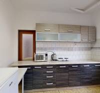 A kitchen in a cottage with white tiles, a microwave, and a double hotplate on the countertop.
