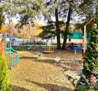 A children's playground surrounded by trees, swings, and climbing frames at Gazárka in Šaštín-Stráže.