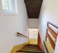 A staircase in a cabin with a window and wooden railing.