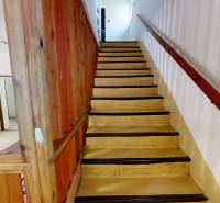 Wooden staircase with wooden railing and wall in the interior of the cabin.