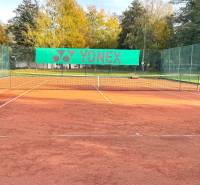 Tennis court at Gazárka in Šaštín-Stráže surrounded by greenery and benches.