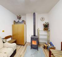 A room in a cottage with a stove, sofas, and decorations, floor with wooden decor.