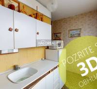 A kitchen in a 3-room apartment with white cabinets and pictures on the walls.