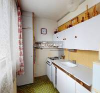 A kitchen in a 3-room apartment with a white cabinet, a gas stove, and vintage decorations.
