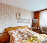 A bedroom in a 3-room apartment with patterned wallpaper and wooden details on the furniture.