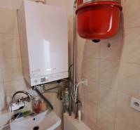 Gas boiler with a sink in commercial premises, tiled floor, walls covered with tiles.