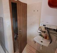 Bathroom in commercial premises with a sink, boiler, and door to the toilet.