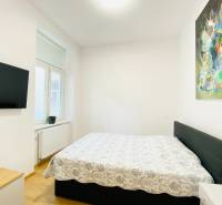 Bedroom with a TV, bed, and abstract painting in a 2-room apartment.