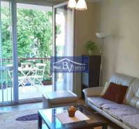 Living room in a 2-room apartment with a spacious balcony and a view of greenery.