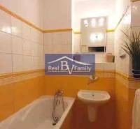 A bathroom in a 2-room apartment with tiles in warm shades and a bathtub.