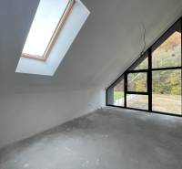 An attic room in a family house with large windows and a view of the forest.