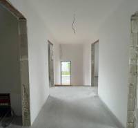 The interior of a family house with white walls and open doors to another room.