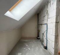 Attic space of a family house with a concrete floor and a skylight.