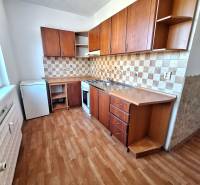 A kitchen in a 3-room apartment with a wooden decor floor and wooden cabinets.