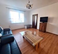 Living room with a sofa, table, and television, wooden decor flooring in a 3-room apartment.