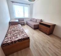 A room in a 3-room apartment with a wooden decor floor, an armchair, and a bed.