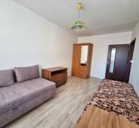 Living room in a 3-room apartment with a wooden decor floor and simple furniture.