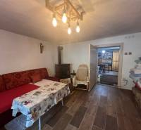 A comfortable room in a cabin with cozy seating, a fireplace, and a wooden ceiling.