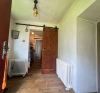 Interior of a cabin with a wood-patterned floor, a radiator, and a sliding wooden door.