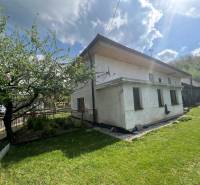 A cottage in Šípkov surrounded by greenery, a fenced garden with trees and a meadow.