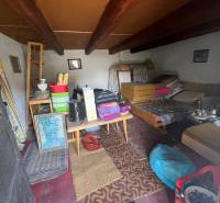 The interior of an unused cottage with rustic furniture and ceiling beams.