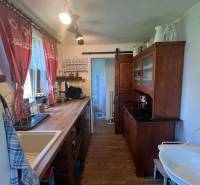 A kitchen in a wooden cabin with rustic furniture, a sink, and decorative curtains.