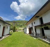 A cottage in Šípkove with a lawn and hilly landscape in the background.