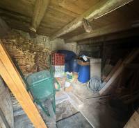 A wooden cabin with supplies of wood, barrels, and tools. A rustic attic suitable for storage.