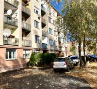 Apartment building on Mederčská in Komárno with parked cars and trees.